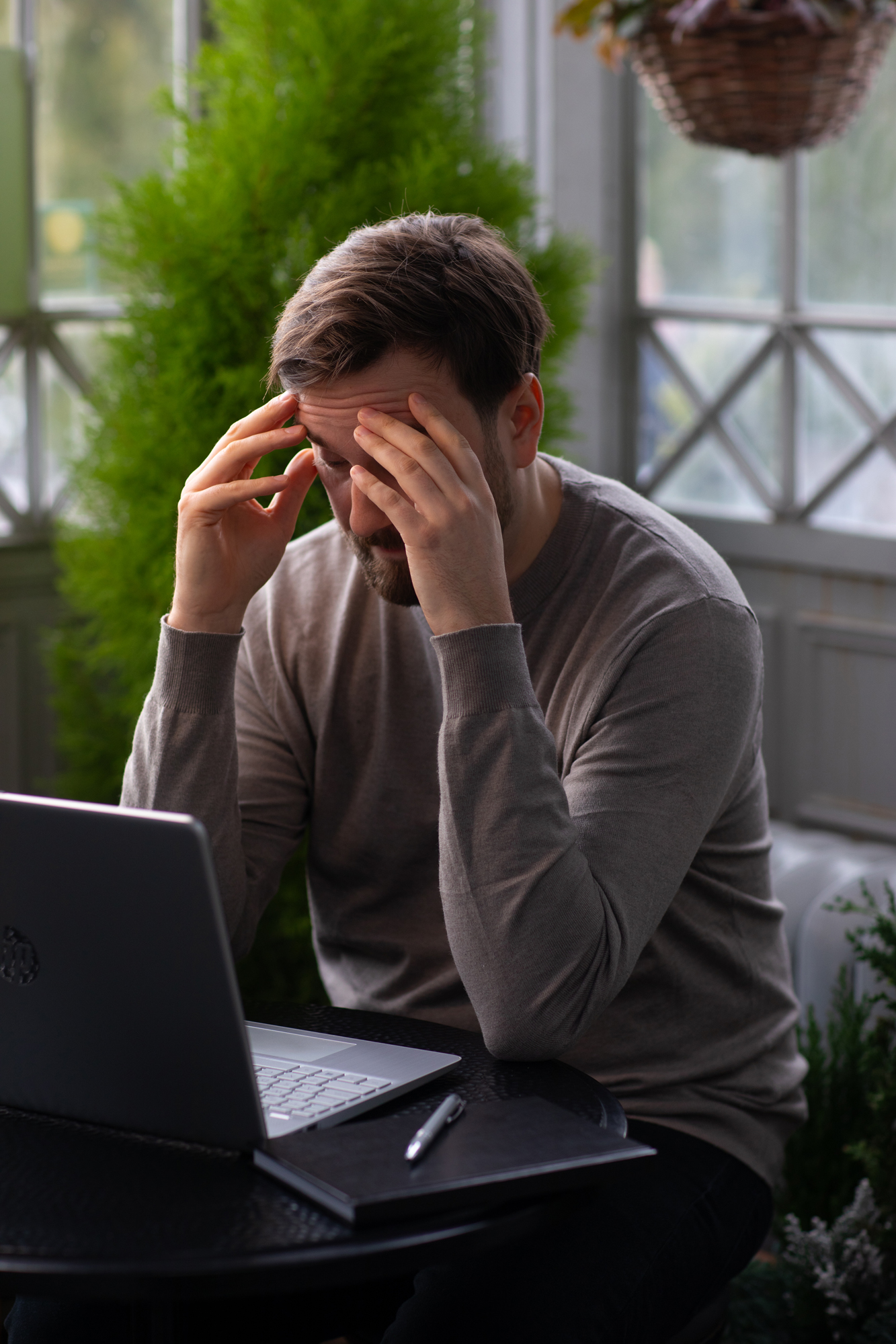 Mies kokee, että arkeen palaaminen on hankalaa ja istuu stressaantuneena tietokoneen ääressä.